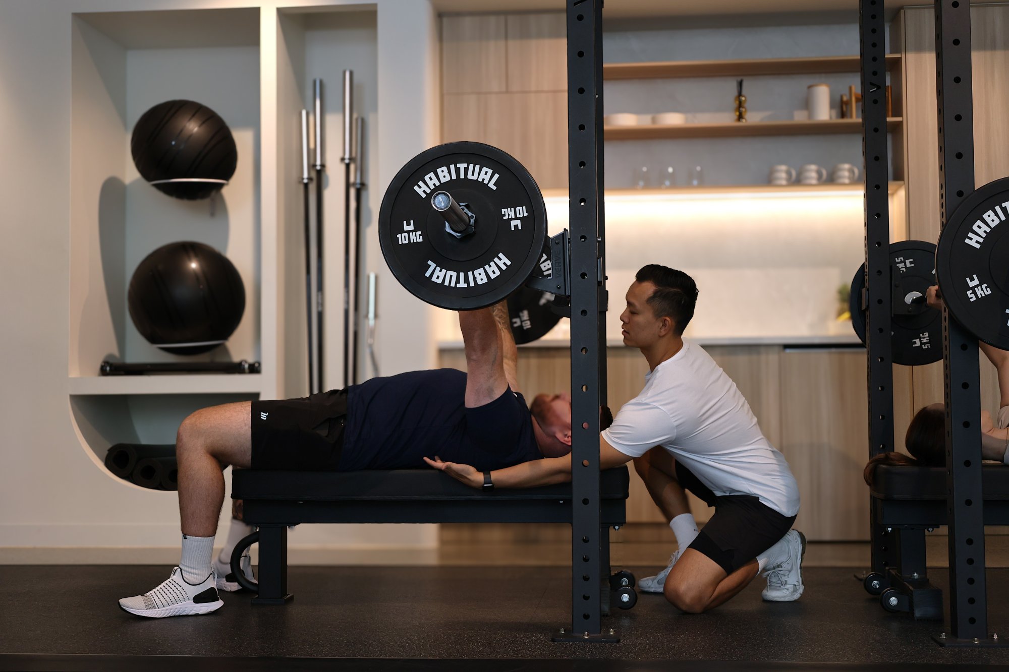A Club Crux coach spotting a member through a bench press
